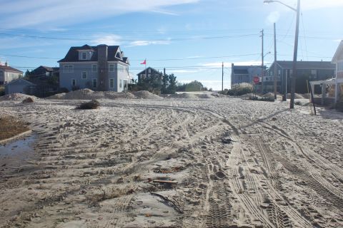 1990 Ford Bronco - Road covered in sand and tire tracks, with houses in the background.