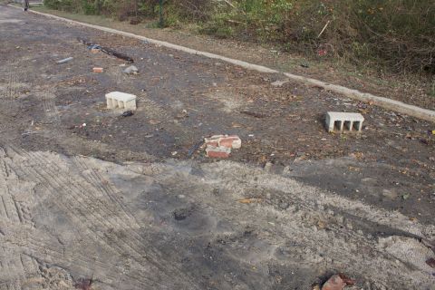 1990 Ford Bronco - The road surface shows signs of damage and debris, with scattered bricks and cinder blocks visible.