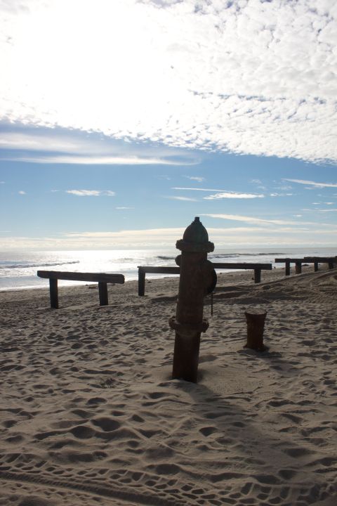 1990 Ford Bronco - Beach scene with a fire hydrant and benches near the ocean.