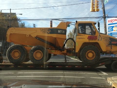 1990 Ford Bronco - A yellow articulated dump truck is transported on a flatbed trailer.