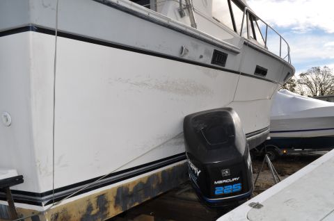 1990 Ford Bronco - A black Mercury 225 outboard motor is visible on the side of a white boat, with another covered boat in the background.