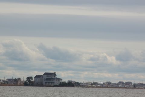 1990 Ford Bronco - Waterfront homes line the shore under a dramatic, cloud-filled sky.