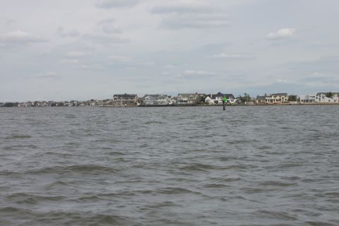 1990 Ford Bronco - View of houses along the coast with a channel marker in the water under a cloudy sky.