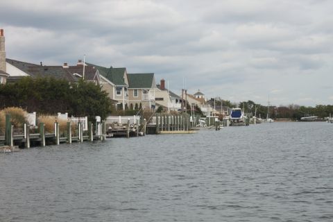 1990 Ford Bronco - A cloudy day over a waterway lined with houses and docks, with a blue boat moored in the distance.