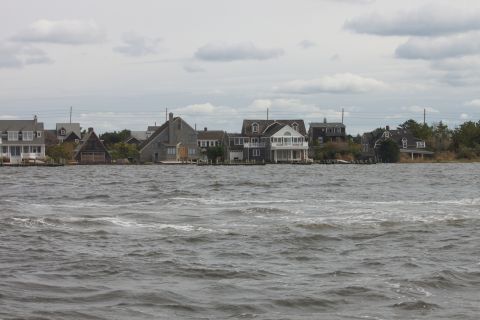 1990 Ford Bronco - Waterfront houses line the shore under an overcast sky.