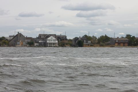 1990 Ford Bronco - Houses line the shore under a cloudy sky, with choppy water in the foreground.