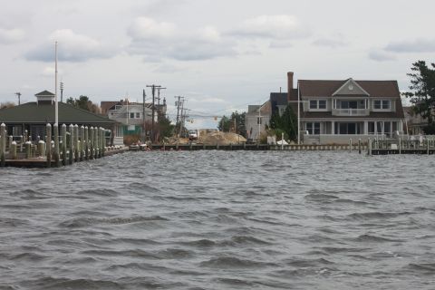 1990 Ford Bronco - Waterfront scene with houses, docks, and choppy water under an overcast sky.