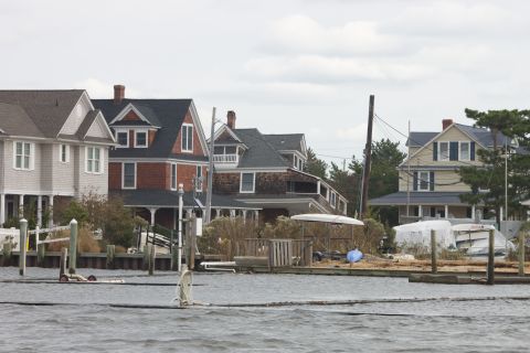 1990 Ford Bronco - A waterfront scene shows houses and boats covered in protective tarps, likely after a storm.