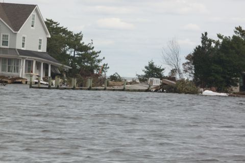 1990 Ford Bronco - A house and dock are submerged in floodwaters, indicating significant storm damage.