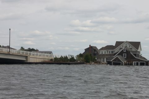 1990 Ford Bronco - Water levels are high around coastal homes and a bridge, indicating significant flooding.