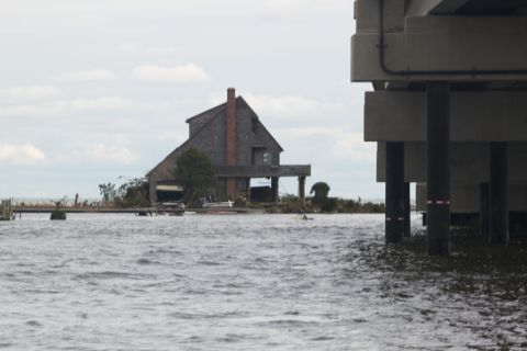 1990 Ford Bronco - A house stands on stilts in flooded waters, with a bridge structure to the right.