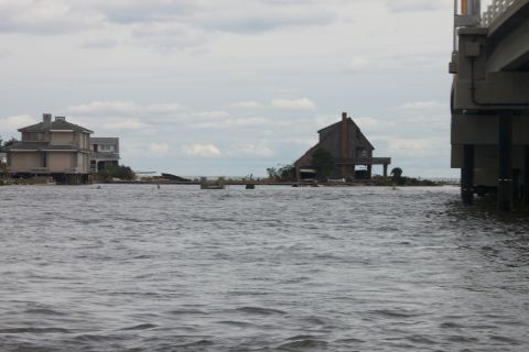 1990 Ford Bronco - Water levels are high around coastal homes, with a bridge structure visible on the right side of the frame.