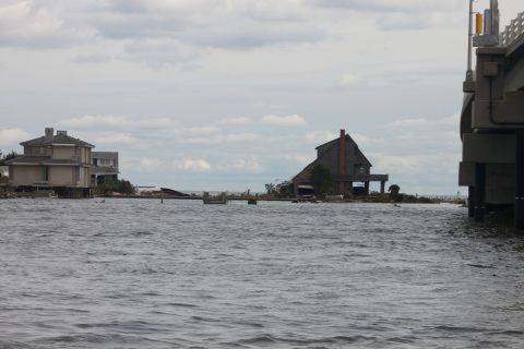 1990 Ford Bronco - A flooded landscape shows houses on stilts and debris under a cloudy sky.