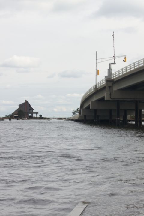 1990 Ford Bronco - A bridge spans over water, with a solitary house visible on a small island in the distance.