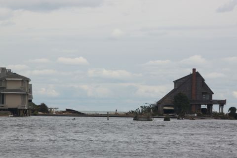 1990 Ford Bronco - Houses submerged in water with debris scattered around, indicative of severe flooding.