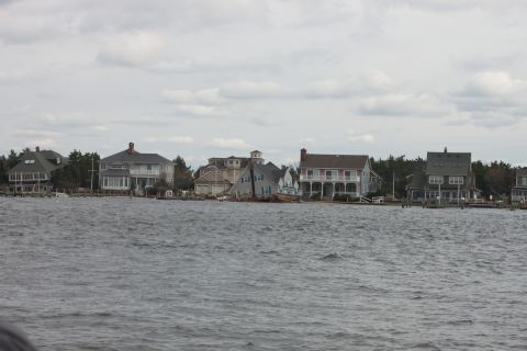 1990 Ford Bronco - A row of waterfront houses lines the shore under an overcast sky.