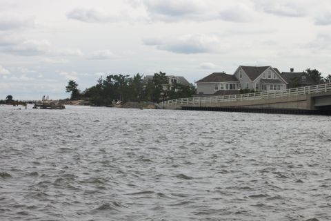 1990 Ford Bronco - Waterfront houses and a bridge are visible under an overcast sky.