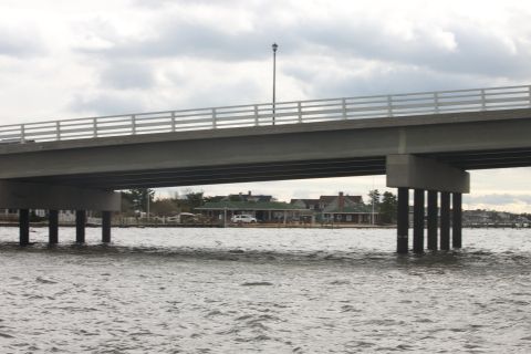 1990 Ford Bronco - A white SUV is visible parked near some buildings under a bridge over the water.
