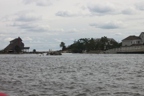 1990 Ford Bronco - A waterfront scene shows houses and debris scattered along the shore under a cloudy sky.