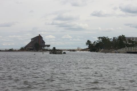 1990 Ford Bronco - A flooded coastal landscape shows houses on stilts and debris after a storm.