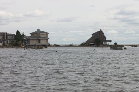 1990 Ford Bronco - Coastal homes submerged in water following a storm, with debris visible in the distance.