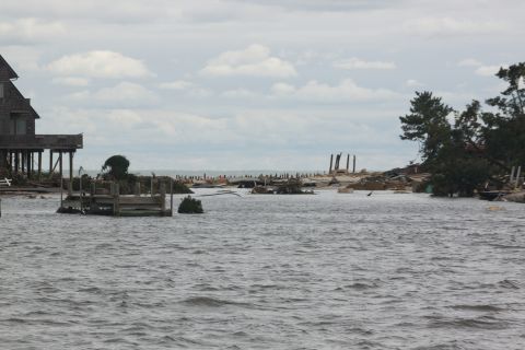 1990 Ford Bronco - The aftermath of a storm shows a flooded area with debris and damaged structures along the coast.