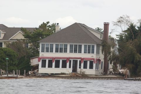 1990 Ford Bronco - House appears damaged by flooding or storm surge, with debris visible around the foundation.