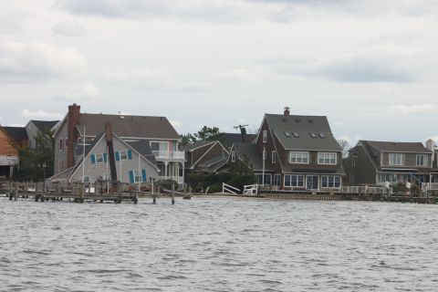 1990 Ford Bronco - Several houses line the waterfront with docks extending into the choppy water under an overcast sky.