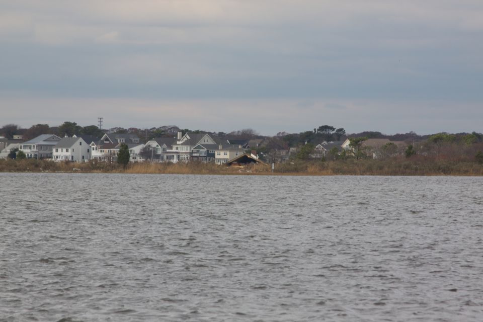 Waterfront houses under a cloudy sky, with a damaged structure in the middle