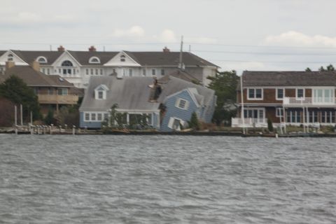 1990 Ford Bronco - Waterfront houses show damage from a storm, with one house significantly tilted.