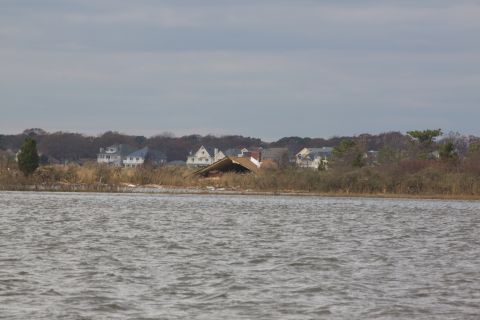 1990 Ford Bronco - Houses on the shore show damage, with one roof completely collapsed.