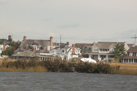 1990 Ford Bronco - A waterfront scene shows houses and marsh reeds under an overcast sky.