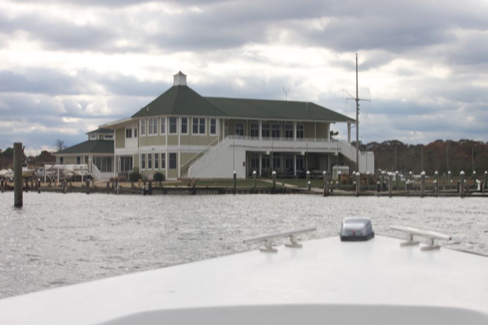 White boat bow with cleat and antenna, overlooking a marina and building