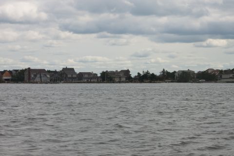 1990 Ford Bronco - A view of houses along the coast with choppy water in the foreground under an overcast sky.