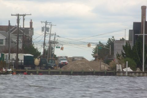 1990 Ford Bronco - A scene of construction and debris cleanup along a waterfront, with multiple vehicles and equipment present.