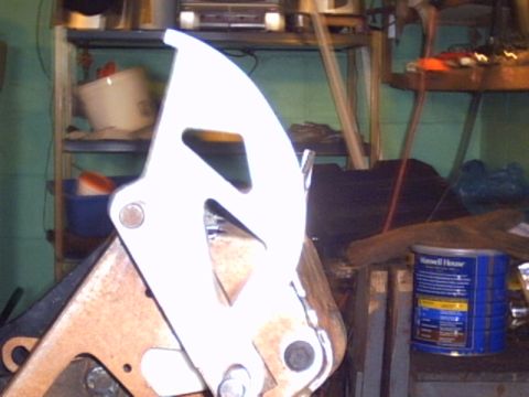 1991 Ford LTD Crown Victoria - A close-up view of a white metal bracket, possibly a car part, in a workshop setting.