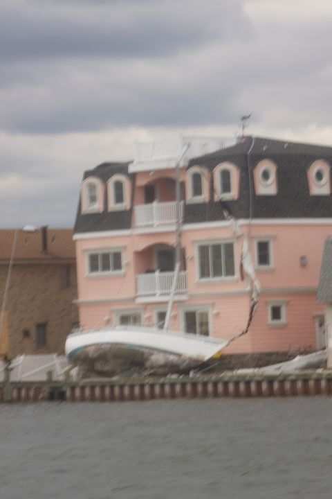 1990 Ford Bronco - A sailboat rests on land near a damaged house, likely a victim of Hurricane Sandy.