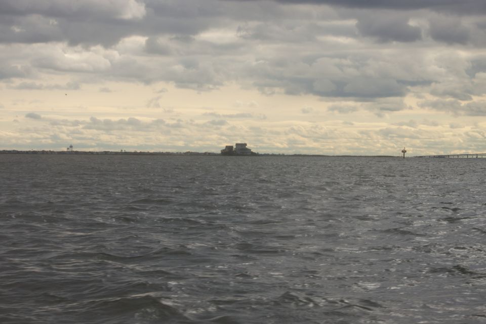 body of water with buildings on the horizon under a cloudy sky
