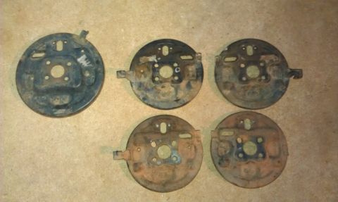 1991 Ford Festiva - Five brake dust shields are laid out on a textured surface. The registry claims they are from a 1991 Ford Festiva.