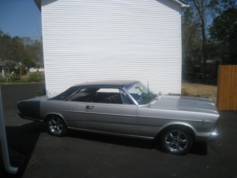 1966 Ford Galaxie - A silver 1966 Ford Galaxie coupe is shown from a three-quarter front angle, parked next to a white building.