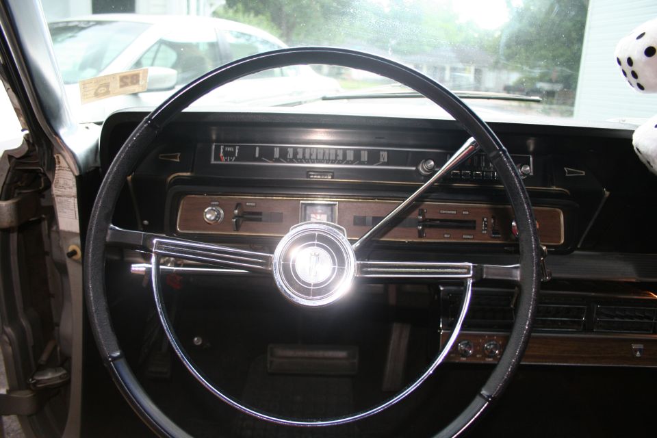1966 Ford Galaxie interior with wood-grain trim, a large steering wheel, and a dashboard with a horizontal speedometer