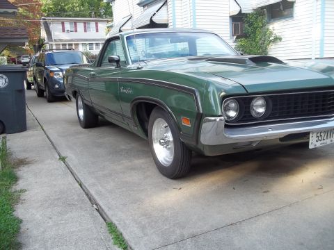 1970 Ford Ranchero - A green 1970 Ford Ranchero pickup truck with racing stripes and a hood scoop is parked on a driveway, with another vehicle visible behind i…