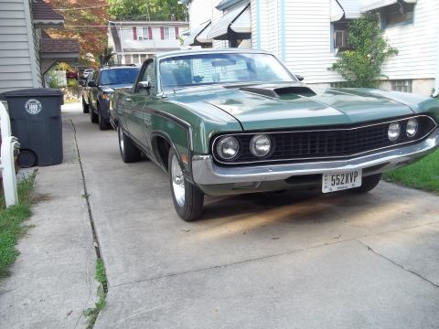 1970 Ford Ranchero - A green 1970 Ford Ranchero is parked in a driveway next to another vehicle.