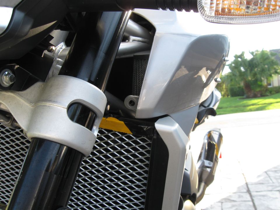 Silver motorcycle front fairing and radiator grille with black forks and a chrome exhaust pipe visible