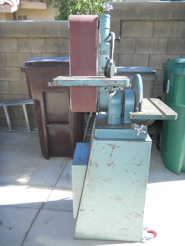 belt sander with two sanding surfaces, one vertical and one horizontal, next to trash cans