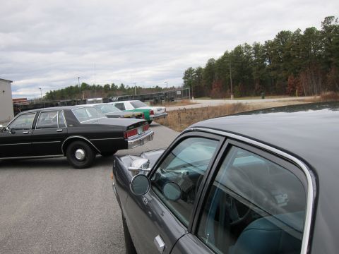 1991 Ford LTD Crown Victoria - Several sedans are parked in an outdoor lot under a cloudy sky.