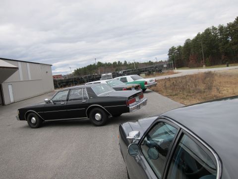 1991 Ford LTD Crown Victoria - Several sedans are parked in a lot under an overcast sky.
