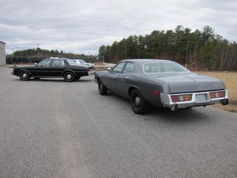 1991 Ford LTD Crown Victoria - Rear view of a grey 1970s Dodge Coronet parked on asphalt, with another dark sedan in the background.