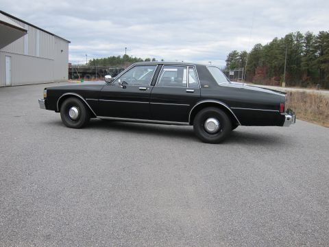 1991 Ford LTD Crown Victoria - Side view of a black sedan parked outdoors on an asphalt surface.