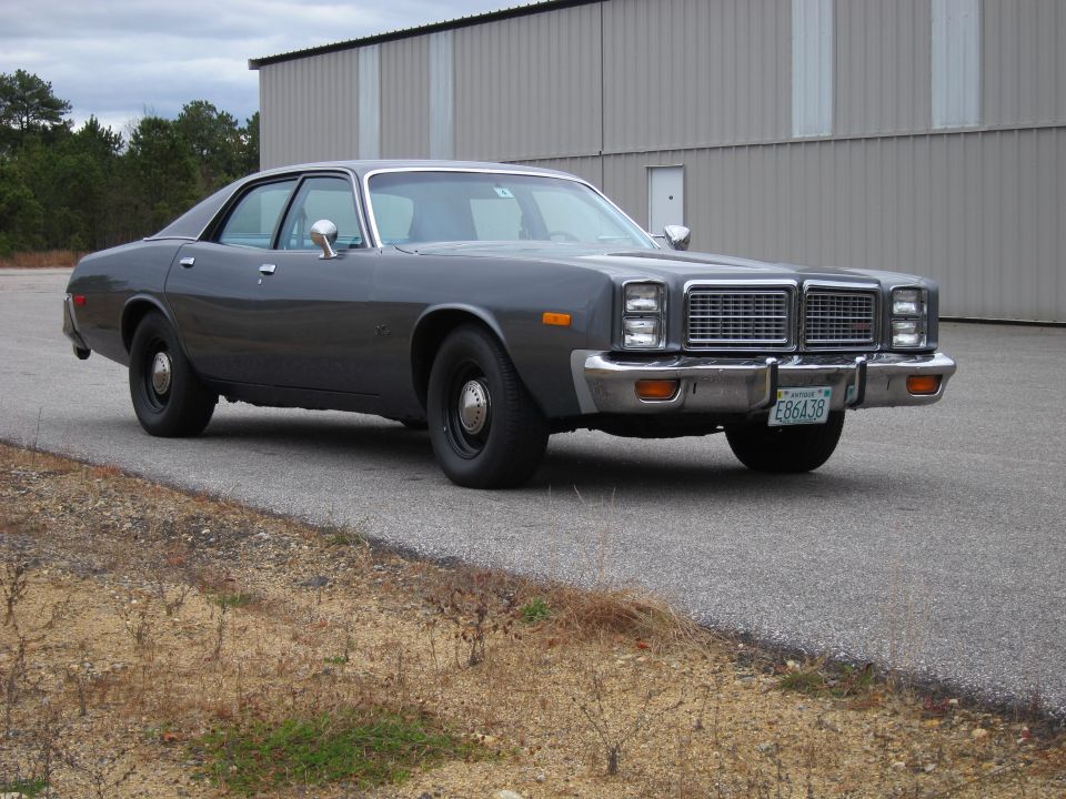 1977 Plymouth Fury sedan parked outside a warehouse, front quarter view. License plate E86438